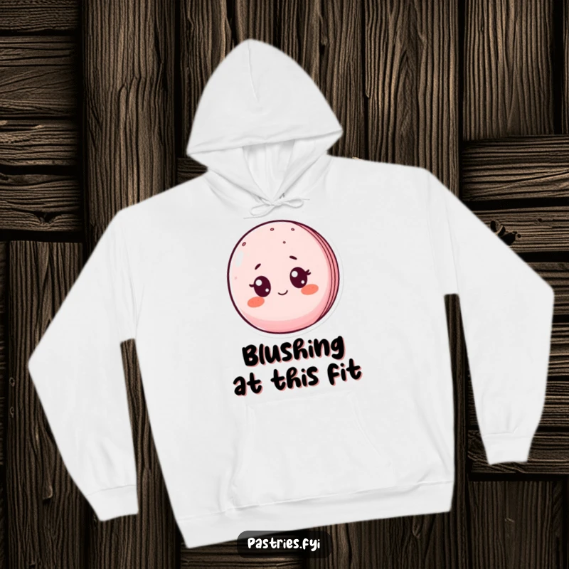 Funny hoodie depicting a blushing macaron character with wide, surprised eyes, offering warmth and a humorous vibe.